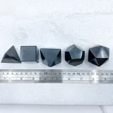 5 Shungite Plutonic Solids lined up next to a ruler