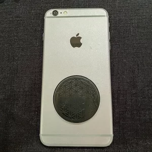 Shungite Flower of Life EMF Protector disc on back of a phone